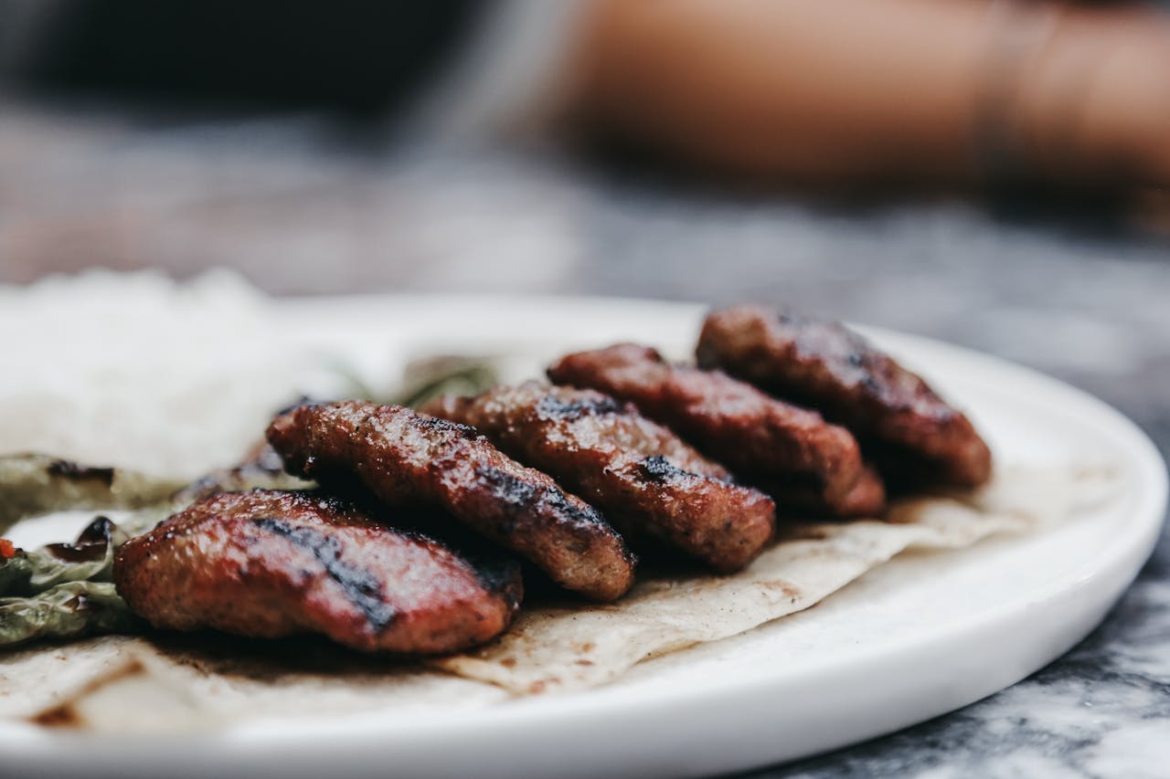 Close-up of grilled beef patties served on a tortilla with rice and vegetables, showcasing a delicious meal.